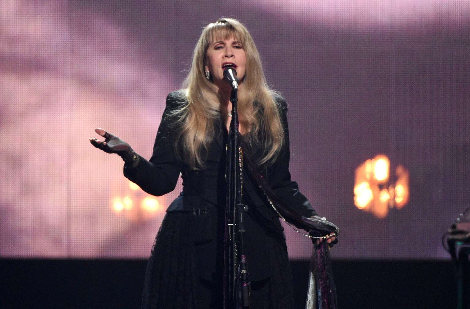 Stevie Nicks steht solo auf der Bühne und singt in Mikrofon