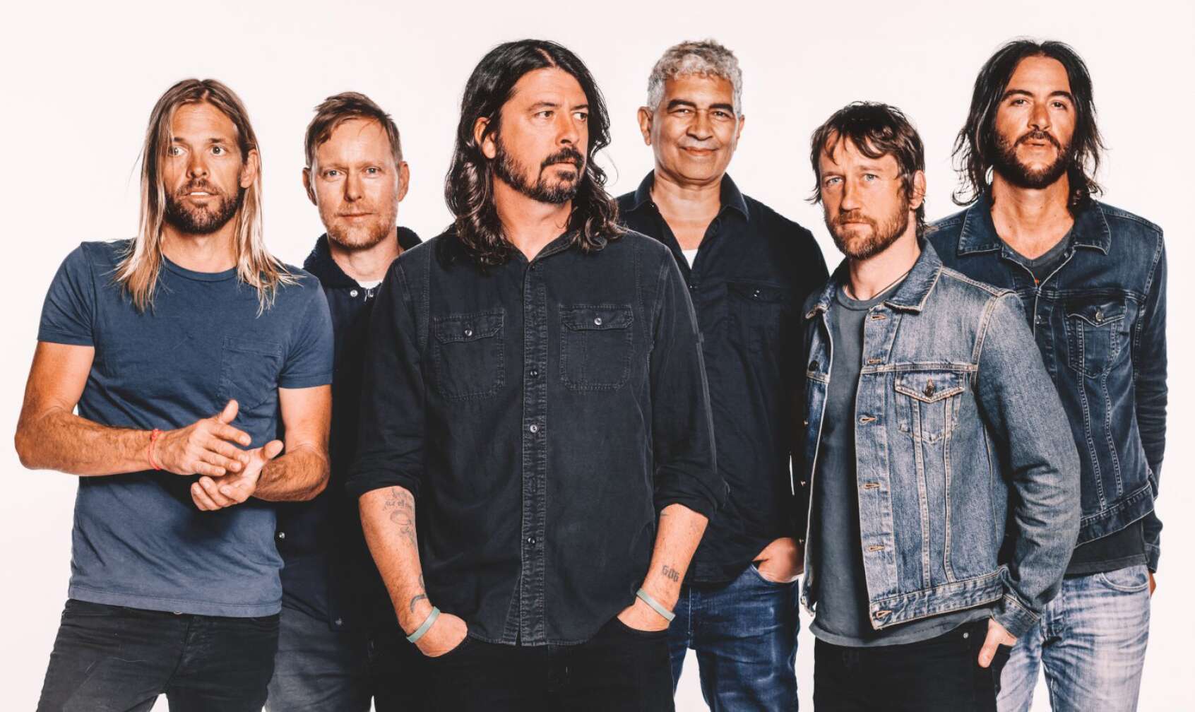 Foo Fighters posieren nebeneinander für ein Pressebild vor weißem Hintergrund