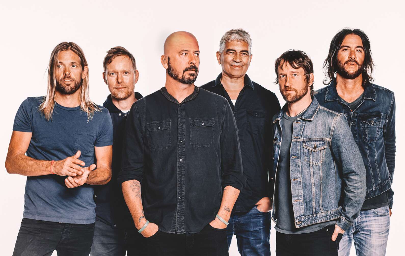 Foo Fighters posieren nebeneinander für ein Pressebild vor weißem Hintergrund