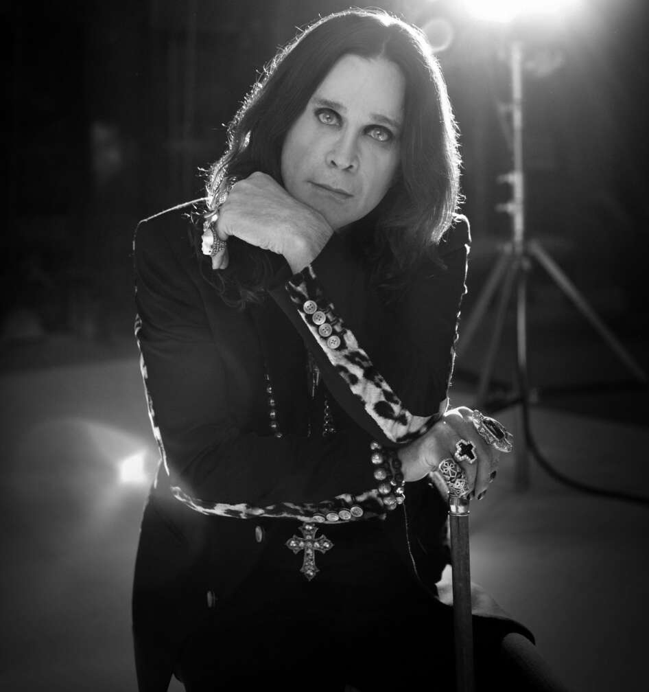 Ozzy Osbourne posiert vor einem Bauscheinwerfer im düsteren Outfit für die Kamera