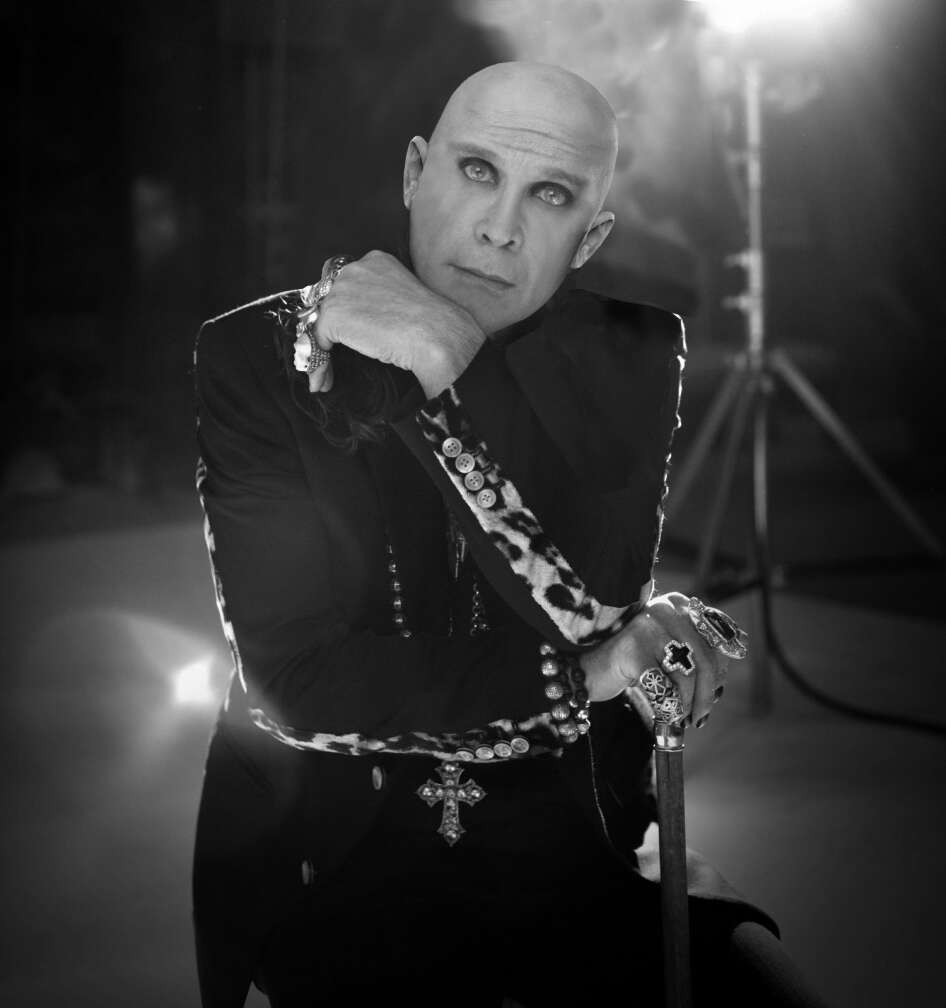 Ozzy Osbourne posiert vor einem Bauscheinwerfer im düsteren Outfit für die Kamera