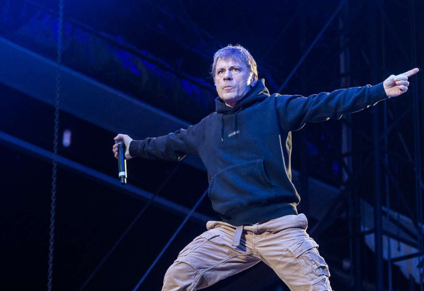 Bruce Dickinson steht in der Hocke, mit Hoodie und Cargohose auf der Bühne