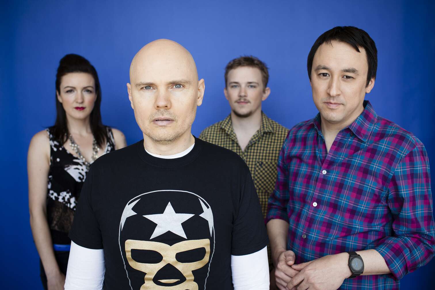 Smashing Pumpkins stehen vor blauem Hintergrund nebeneinander
