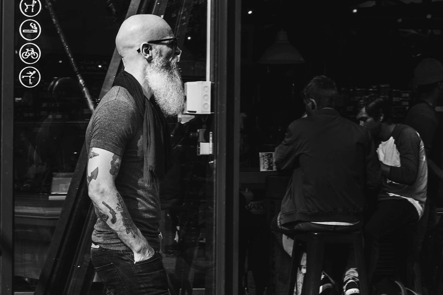 Typ mit Glatze, Rauschebart und Sonnenbrille geht in eine Bar