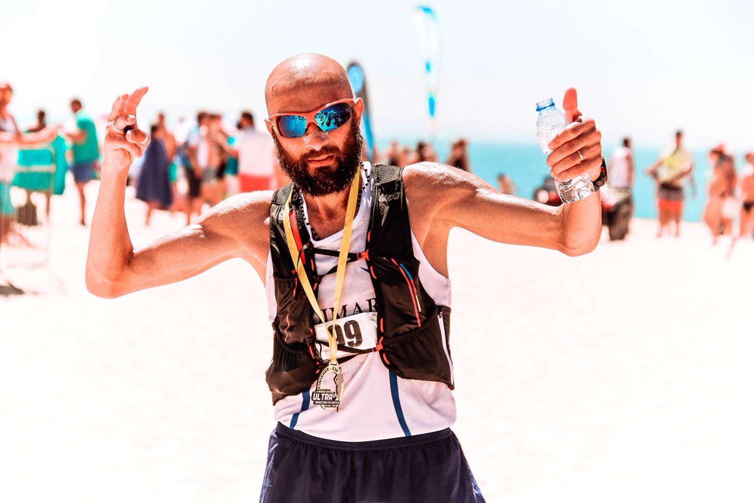 Typ mit Sonnenbrille, Glatze und Wasserflasche in der Hand streckt den Daumen nach oben