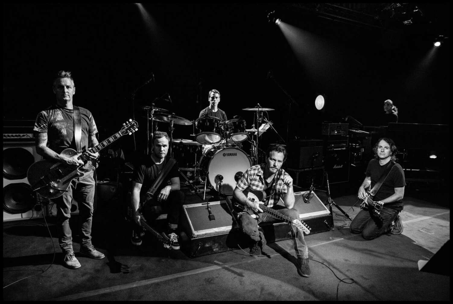 Pearl Jam posieren auf einer Bühne mit ihren Instrumenten