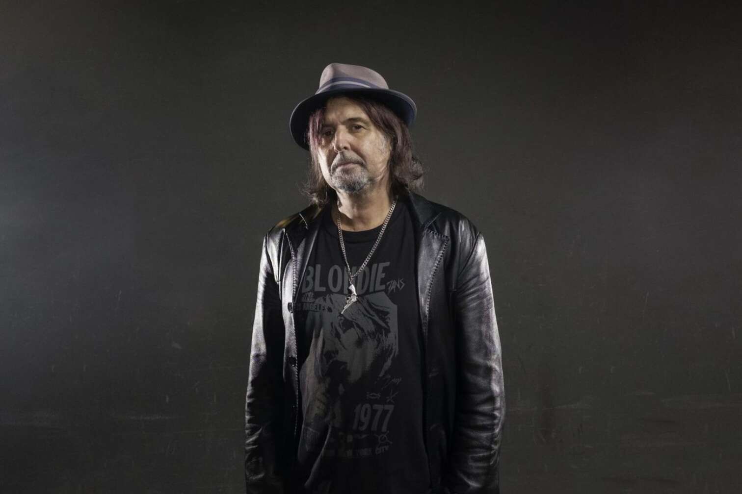 Phil Campbell posiert mit einem Hut und Lederjacke vor einem schwarzem Hintergrund