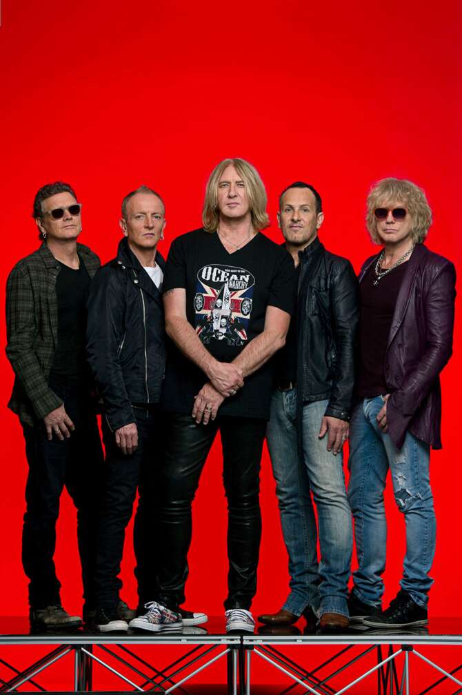 Def Leppard posieren vor rotem Hintergrund