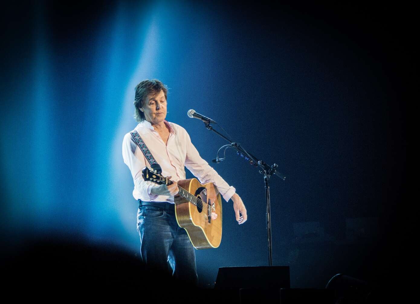 Paul McCartney steht mit seiner Akustik-Gitarre im Scheinwerferlicht