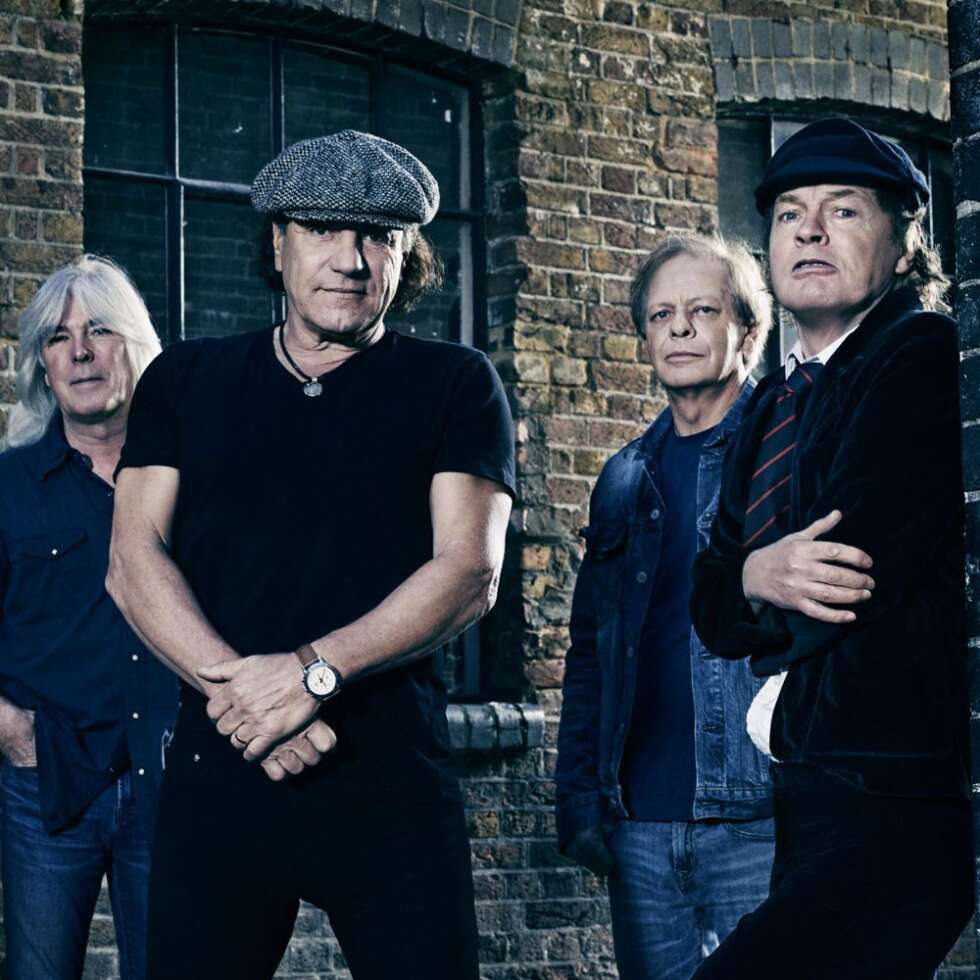 Bandmitglieder von AC/DC posieren vor altem Backsteinbau