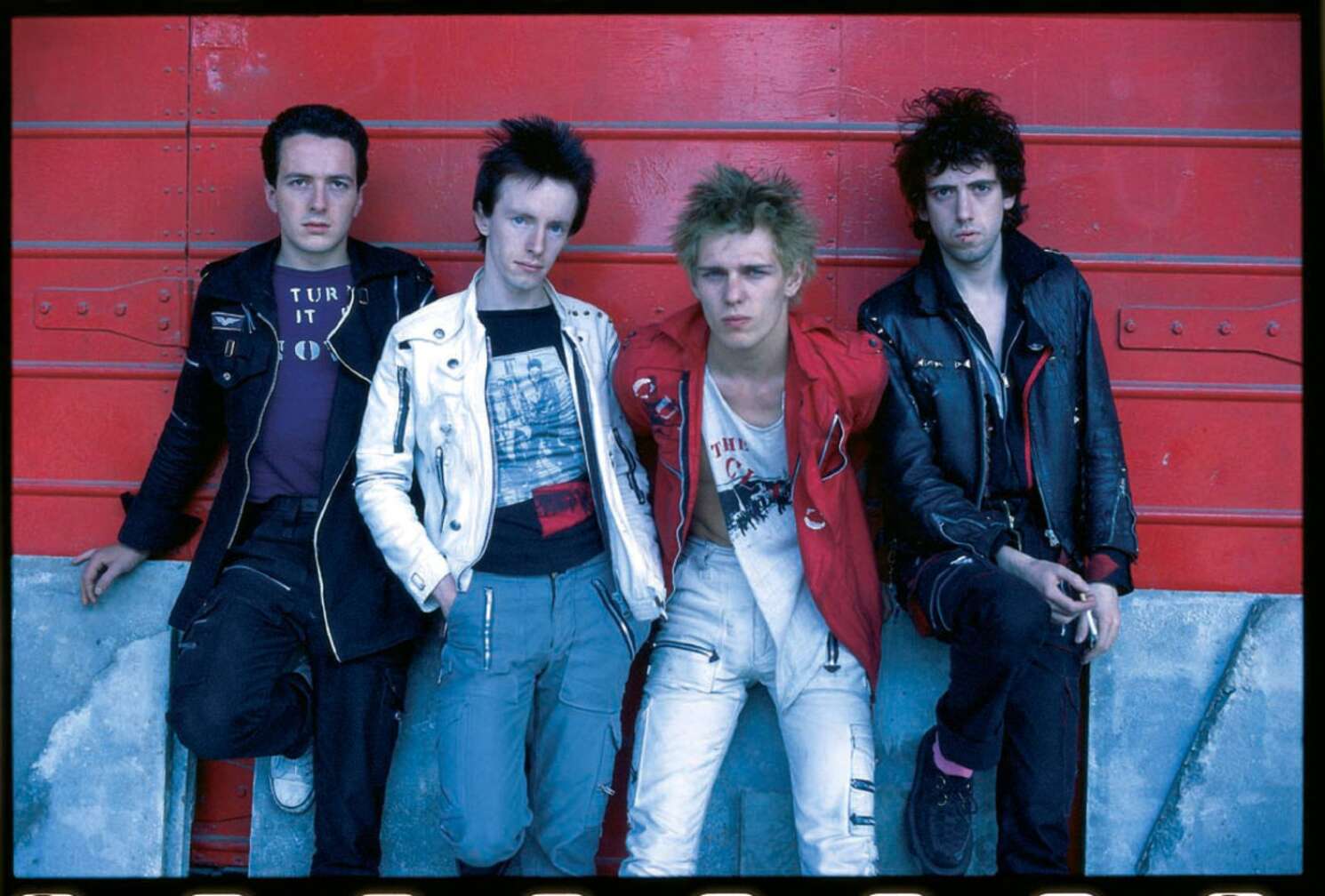 The Clash posieren vor einer roten Wand