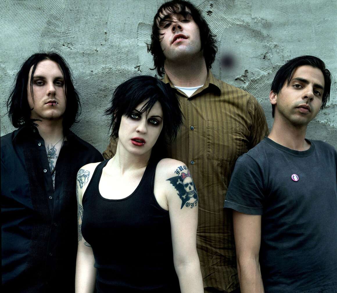 The Distillers posieren vor einer grauen Wand