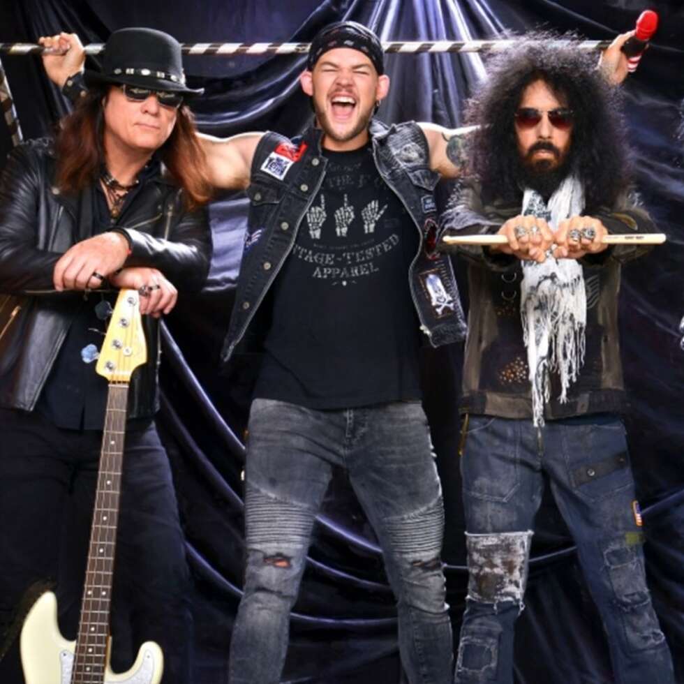 Quiet Riot Sänger James Durbin lachend zwischen zwei weiteren Bandmitgliedern