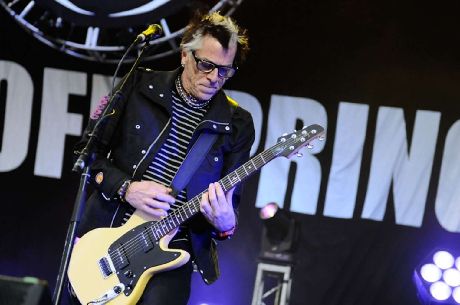 Noodles von "The Offspring" spielt Gitarre auf einer Bühne