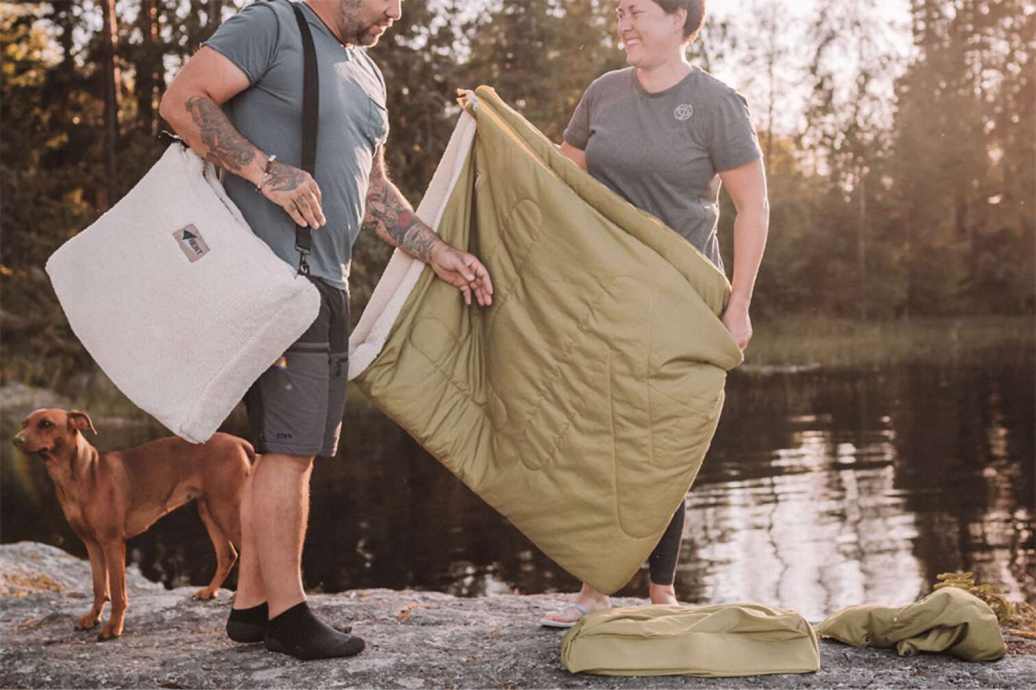 Zwei Menschen an einem Seeufer packen einen Bent Bentcho Schlafsack aus