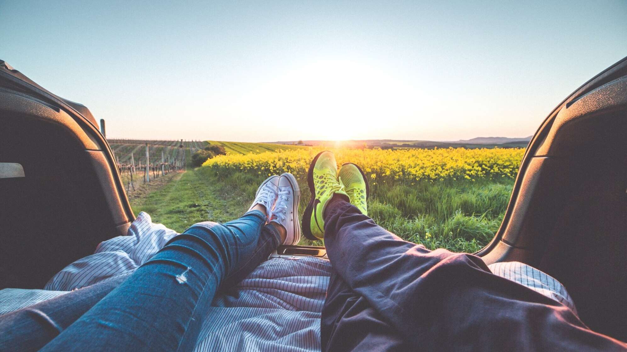 Blick aus Auto Richtung Sonnenuntergang und Wiese