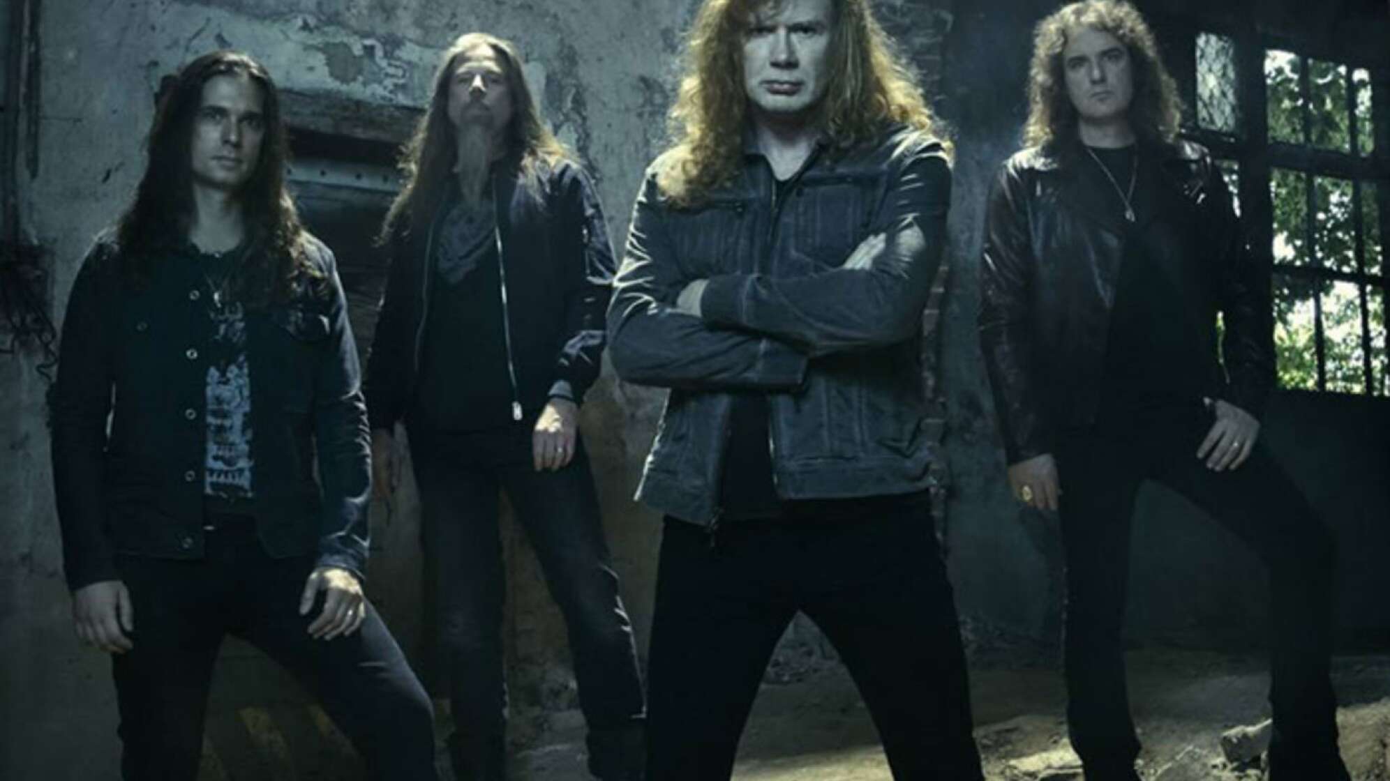 Die Band Megadeth steht in einer dunklen Halle und schaut ernst