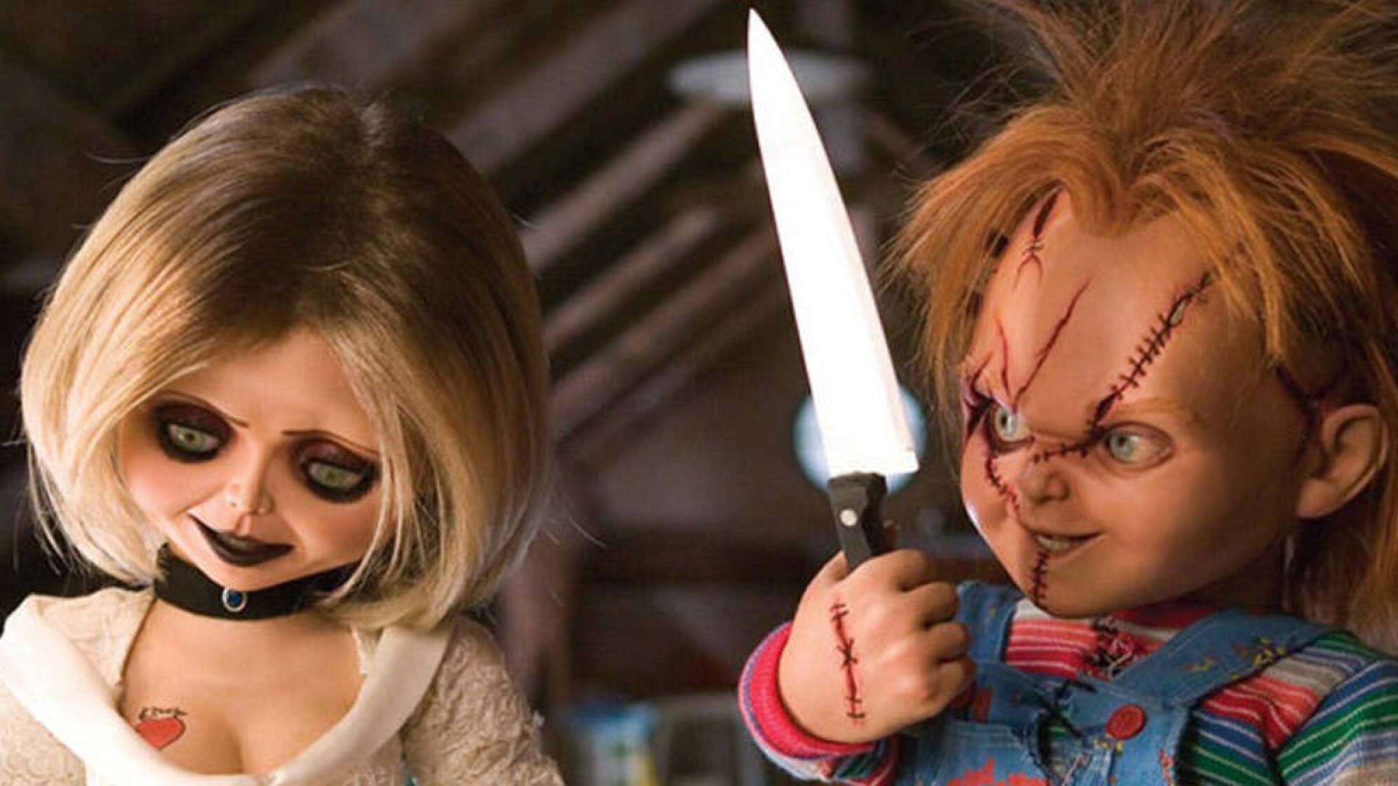 Chucky die Mörderpuppe steht neben einer anderen Puppe
