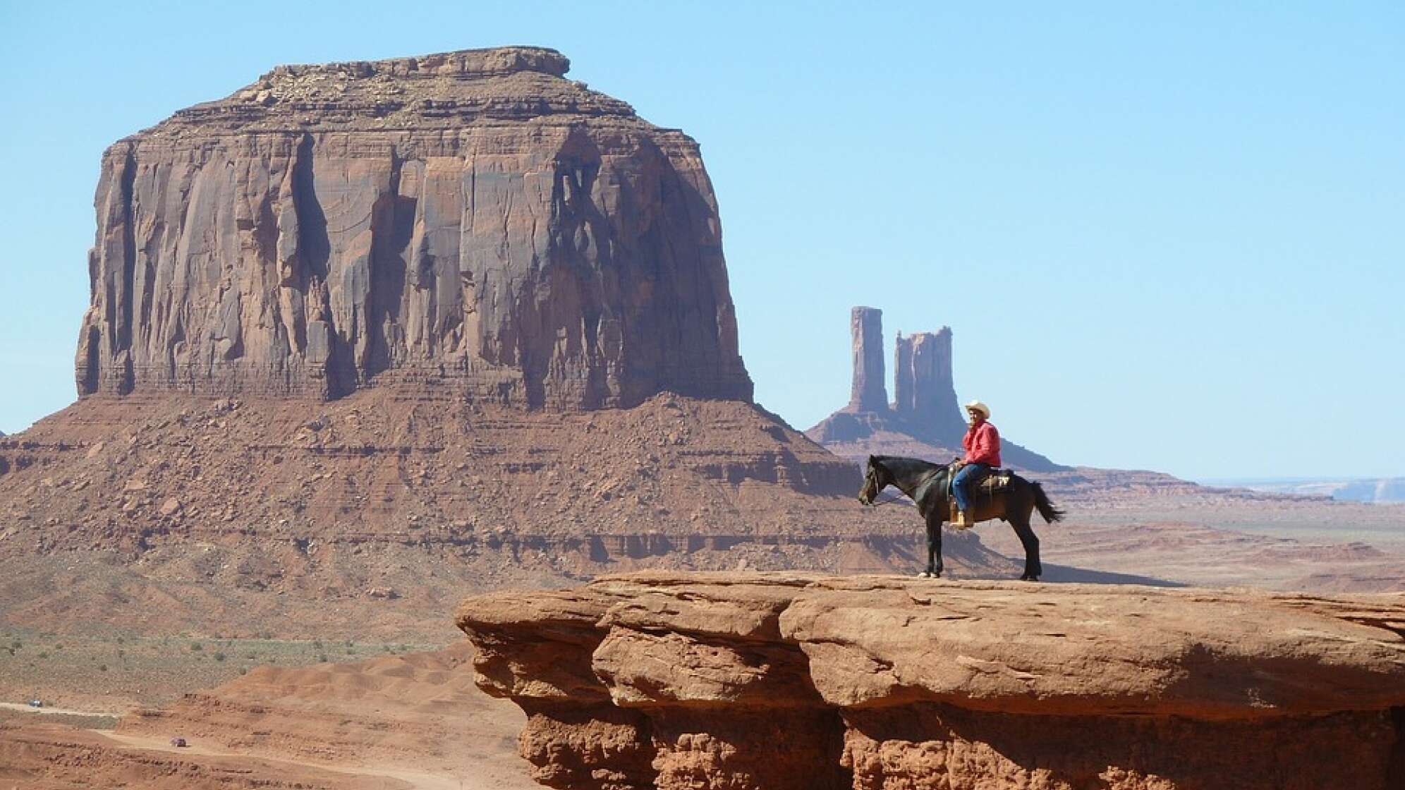 Cowboy steht mit seinem Pferd auf einem Felsen