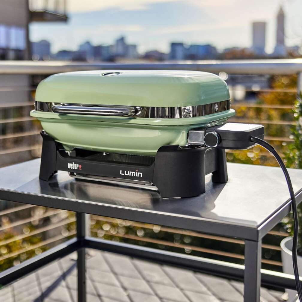 Der Lumin Elektrogrill von Weber steht auf einem Tisch auf einem Balkon