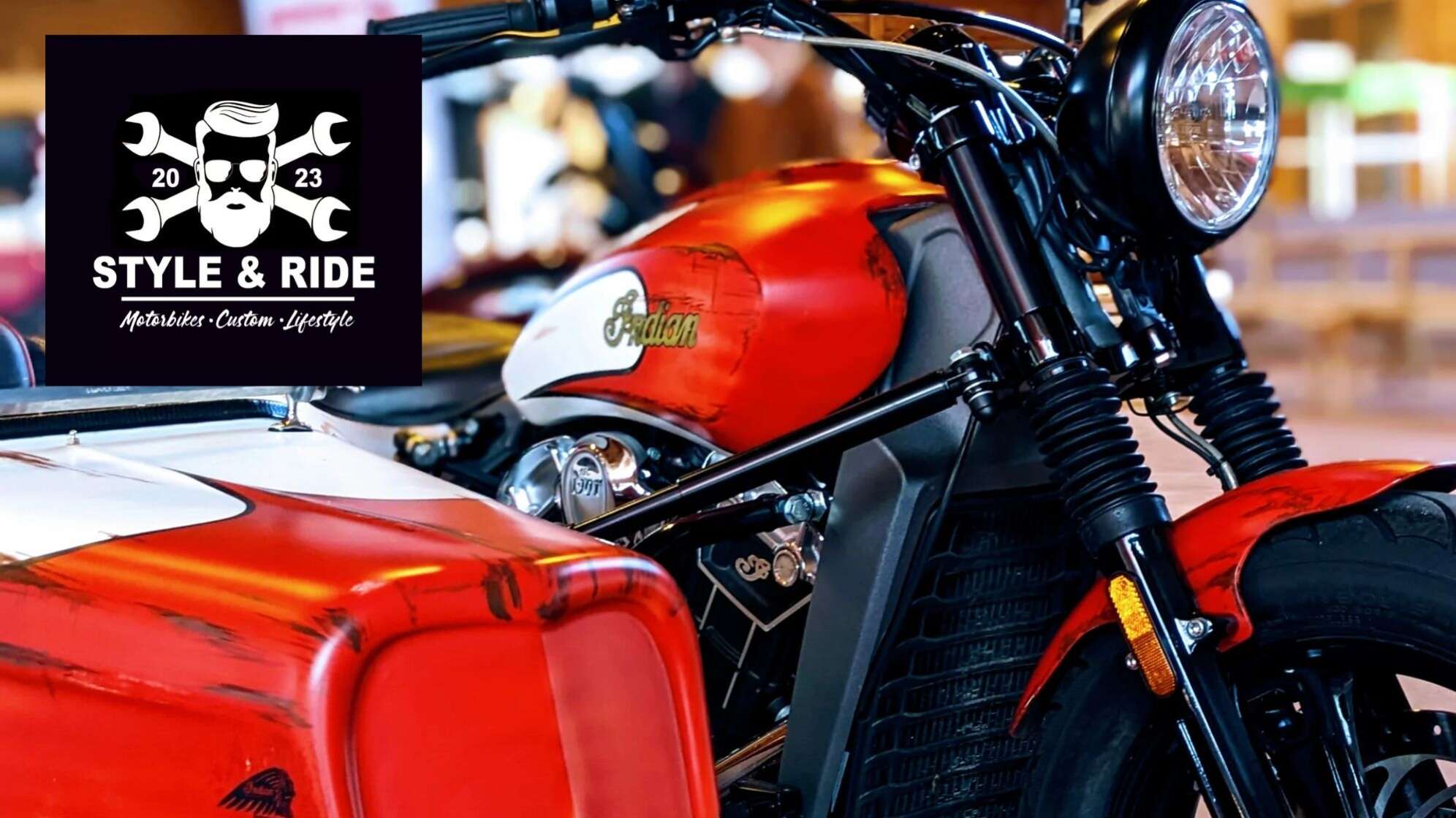 Detailaufnahme eines rot-weißen Indian-Custombikes mit Beiwagen, darüber das Event-Logo „Style & Ride – Motorbikes · Custom · Lifestyle 2023“ mit bärtigem Biker und Schraubenschlüsseln – Motorrad- und Custombike-Event in Bayern.