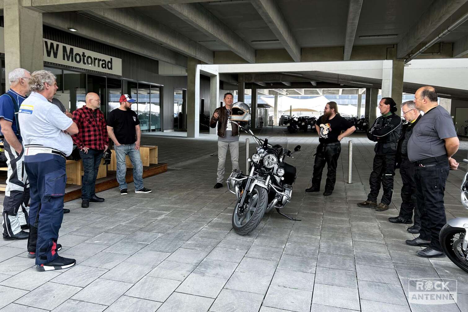 Ein Bild einer Gruppe Motorradfahrer im Halbkreis bei einer Einweisung vor der Filiale von BMW Motorrad München
