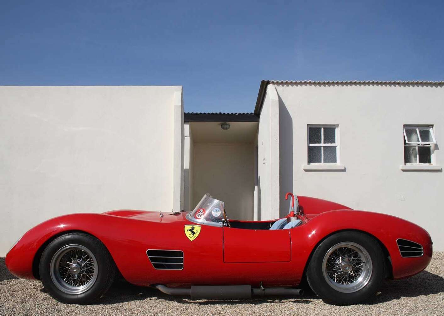 roter Ferrari Dino parkt vor Hauswand