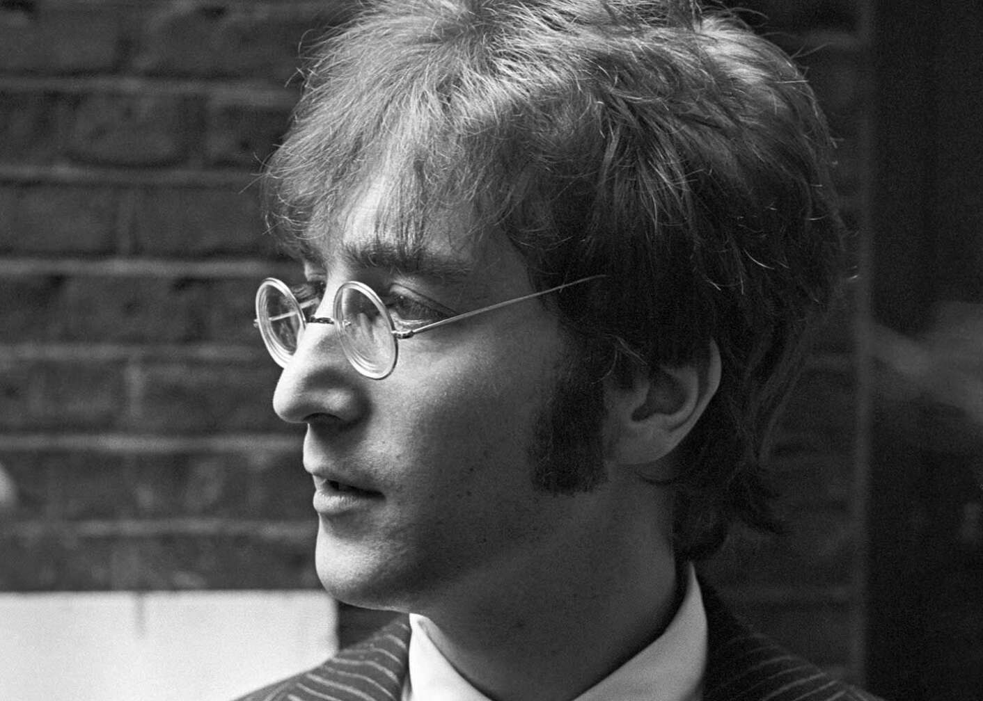John Lennon, mit Brille, blickt zur Seite