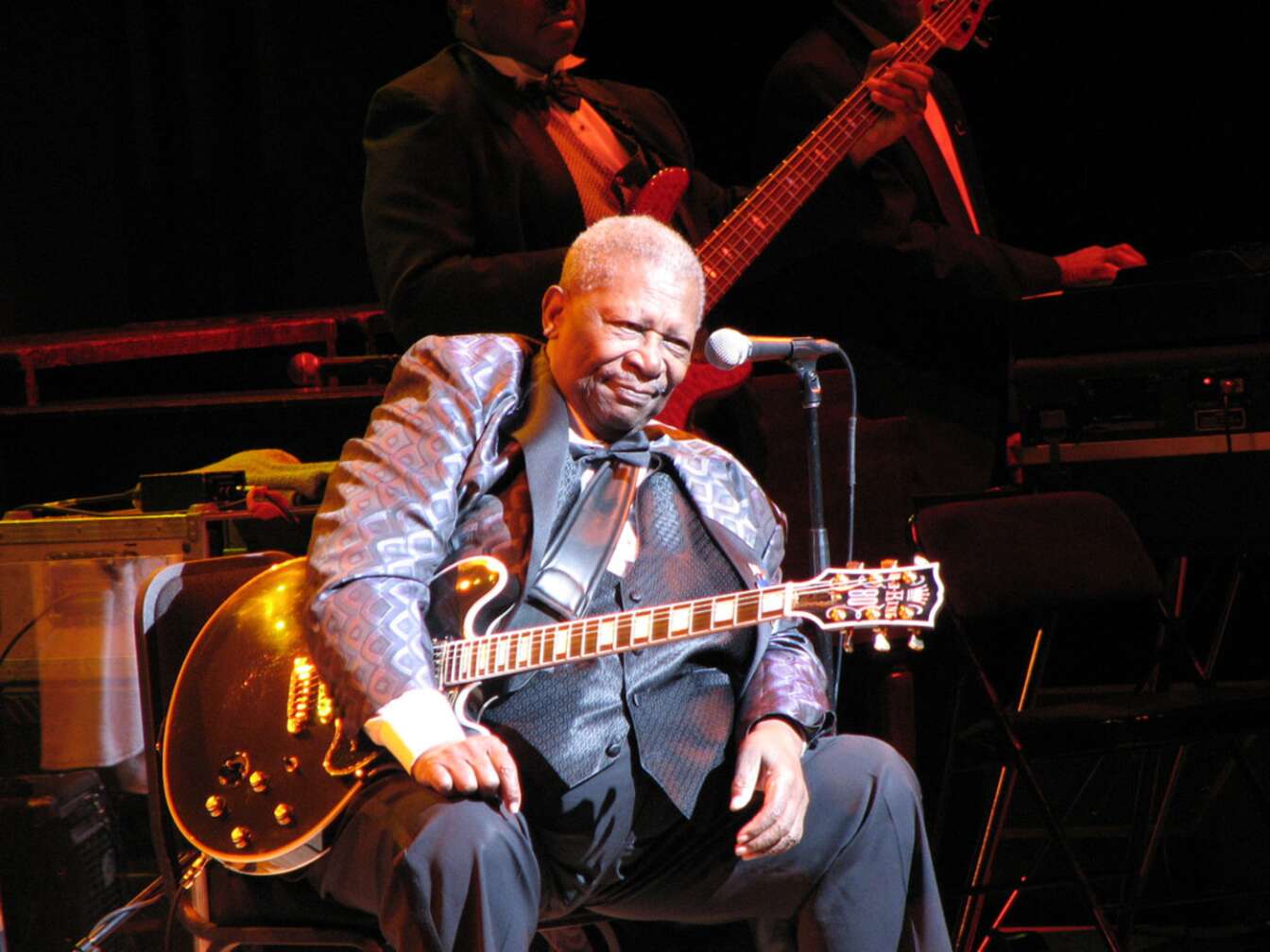 B.B. King sitzend, mit Gitarre, auf der Bühne, ernst schauend