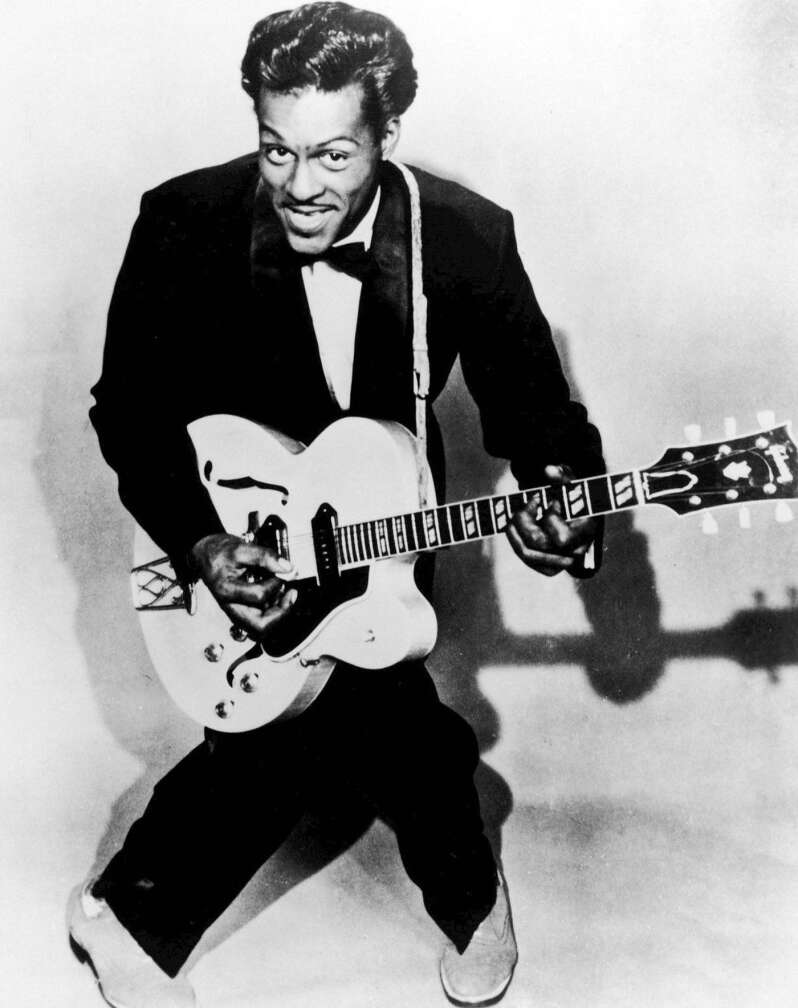 Chuck Berry kniend mit Gitarre, lächelnd