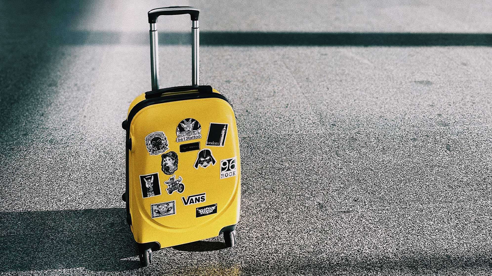 Ein gelber Koffer am Flughafen mit Aufklebern