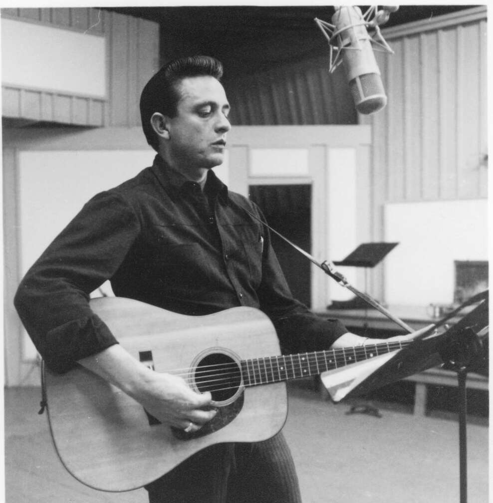 Johnny Cash steht mit Western-Gitarre im Studio und nimmt auf