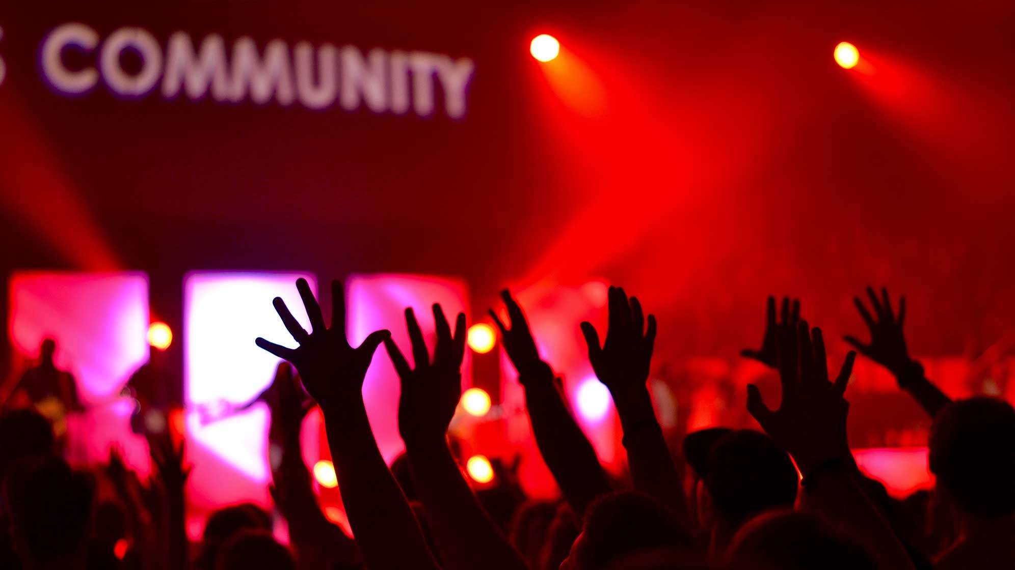 Menschen strecken in einem Club die Hände in die Höhe und sind selbst nur als Silhouetten zu sehen