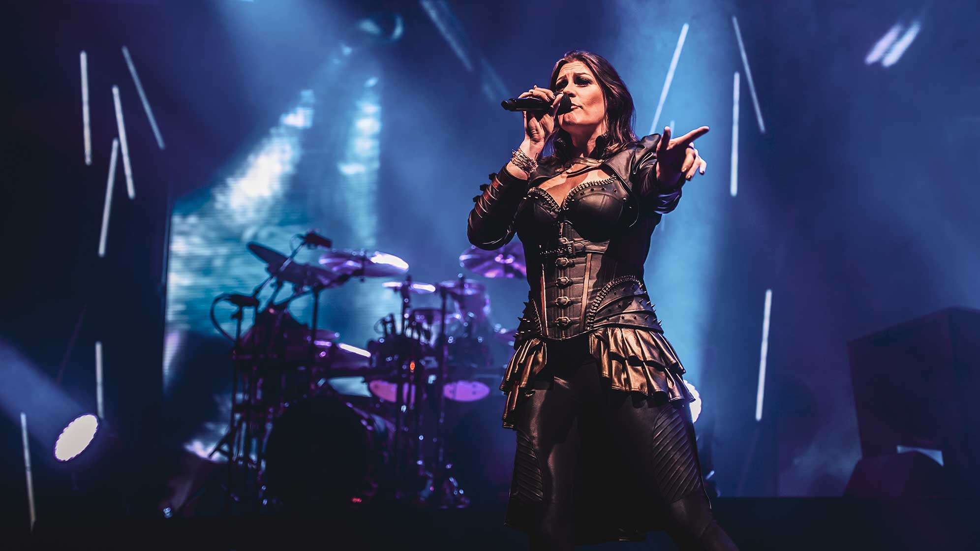 Sängerin Floor Jansen auf der Bühne ihrer Band Nightwish vor blauem Hintergrund.