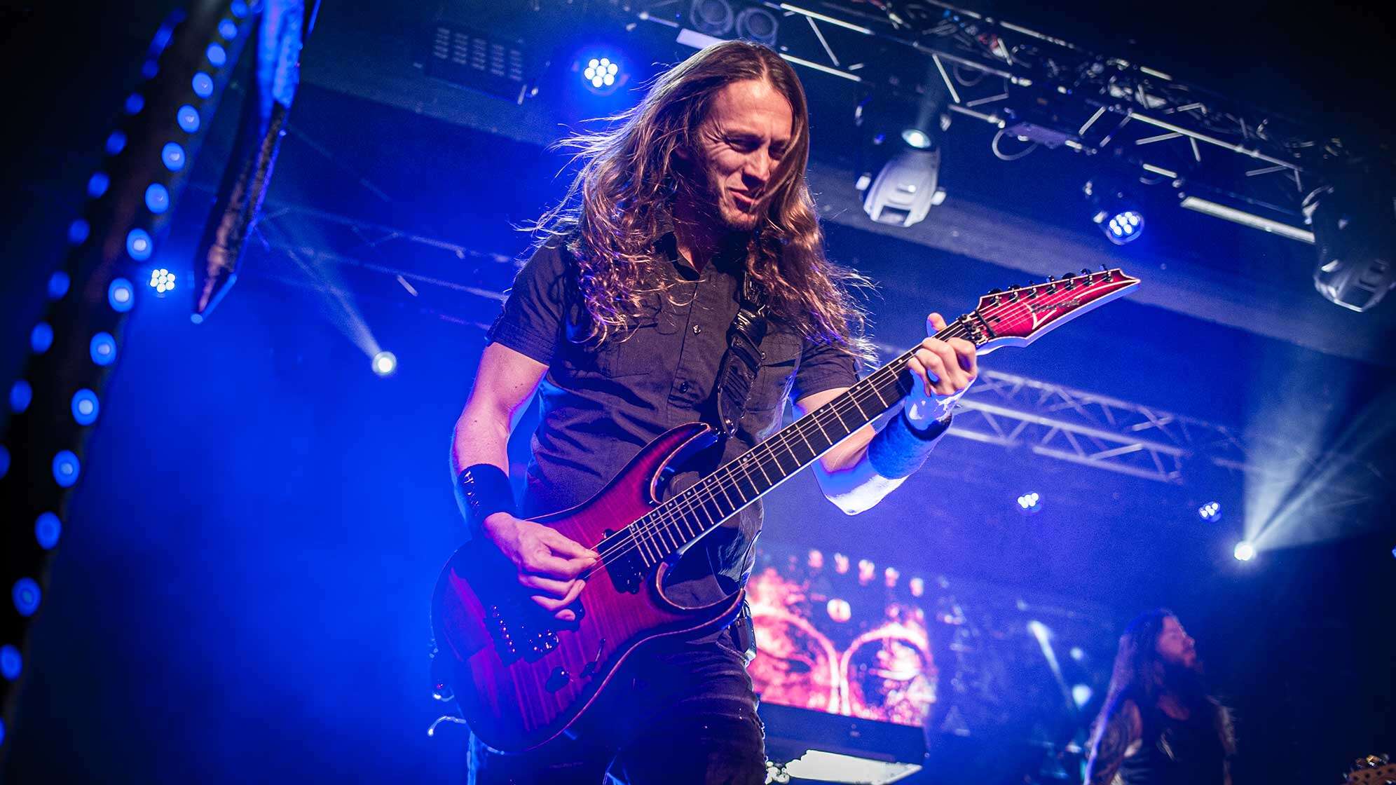 Gitarrist Mark Jansen von Epica steht auf der Bühne - im Hintergrund sieht man eine blaue Beleuchtung.