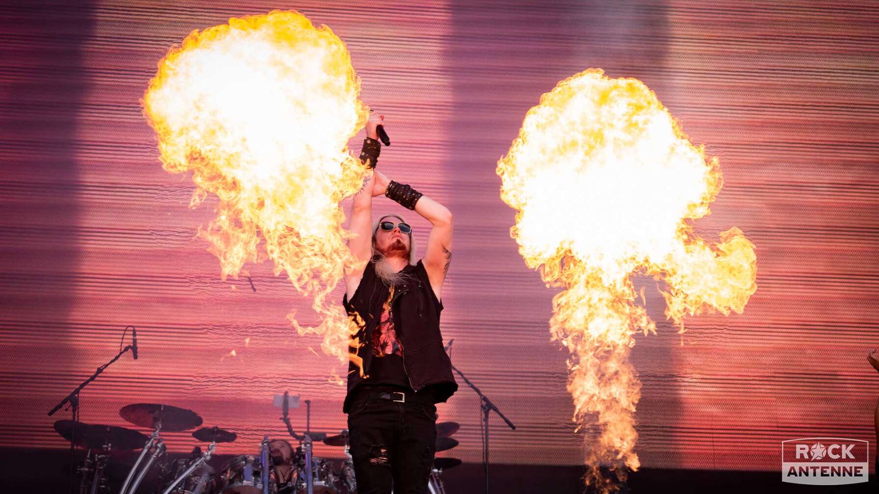 Der Sänger der Band Dragonforce auf der Bühne des Summer Breeze Open Airs - im Hintergrund leuchtet Pyrotechnik.