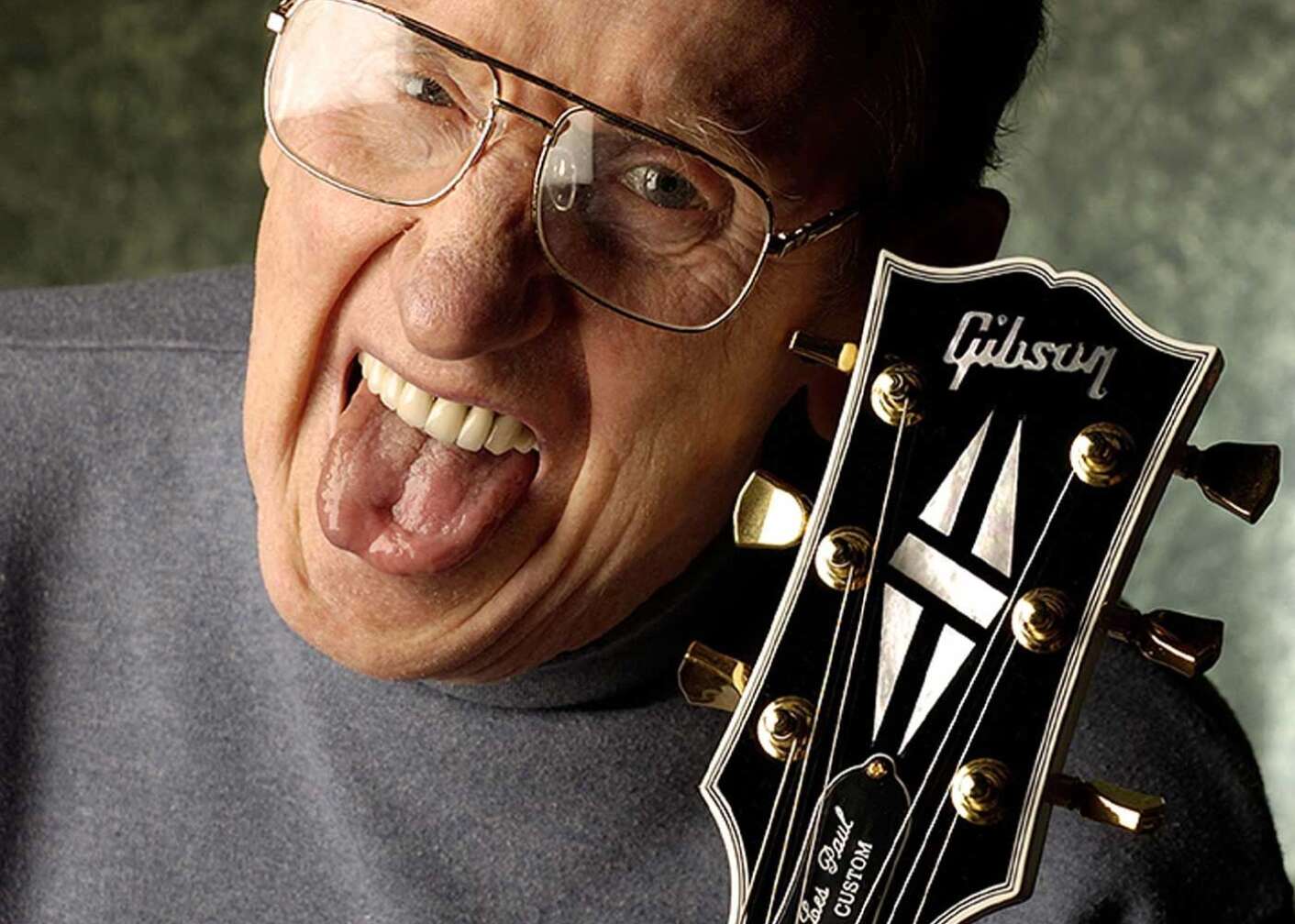 Les Paul-Gründer mit rausgestreckter Zunge und einer Gitarre