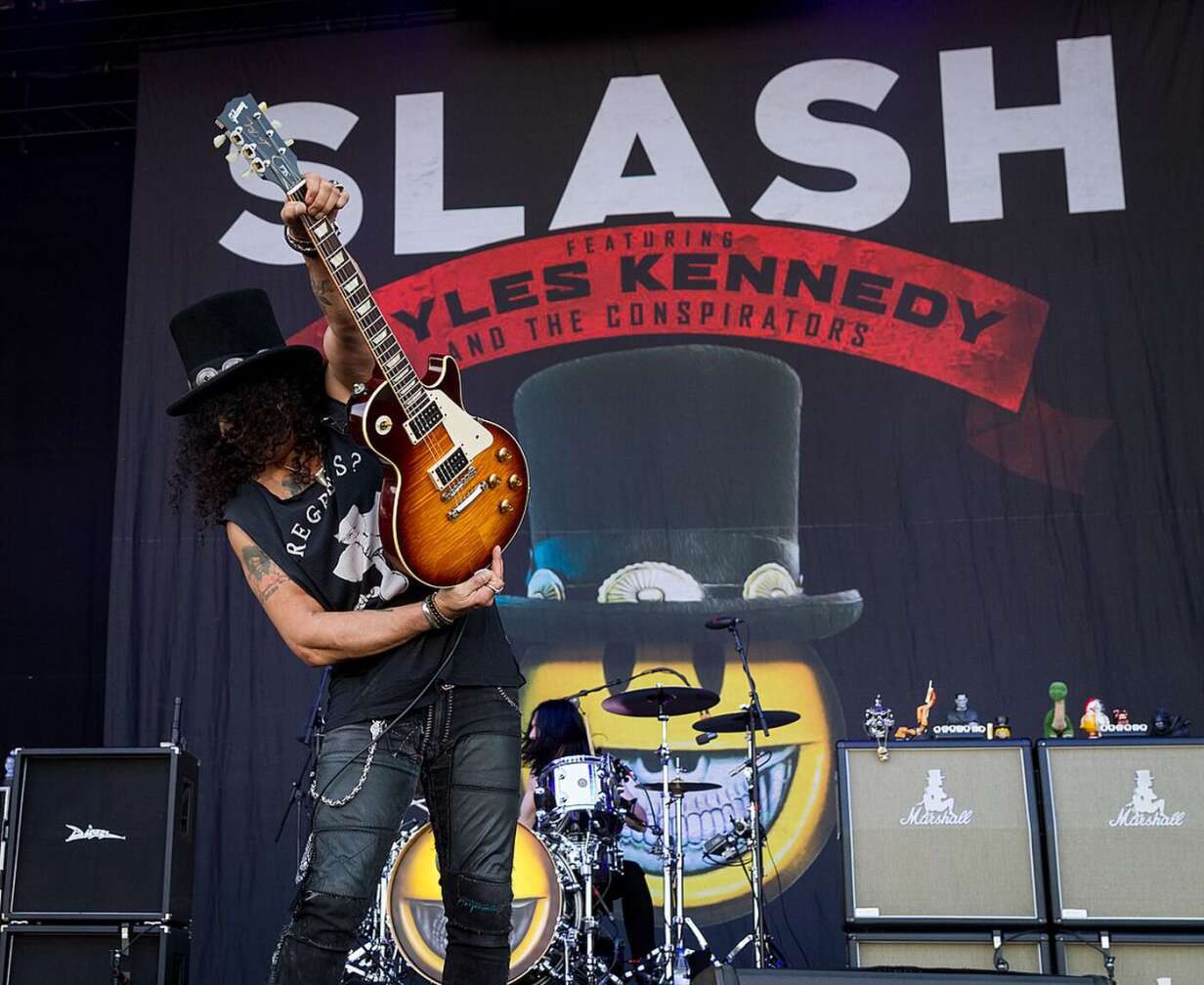 Slash, der eine Les Paul-Gitarre hochhält