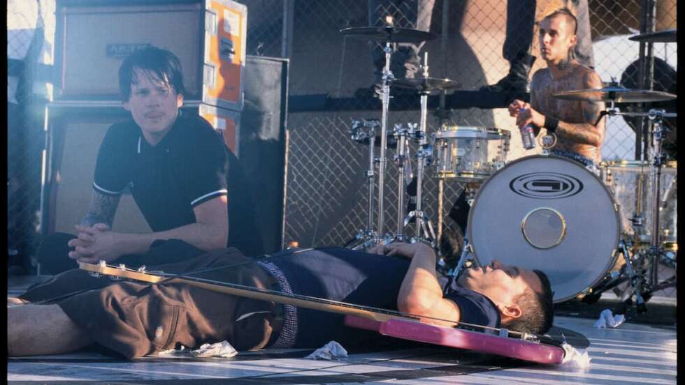 Blink-182 sitzend und liegend auf einer Bühne