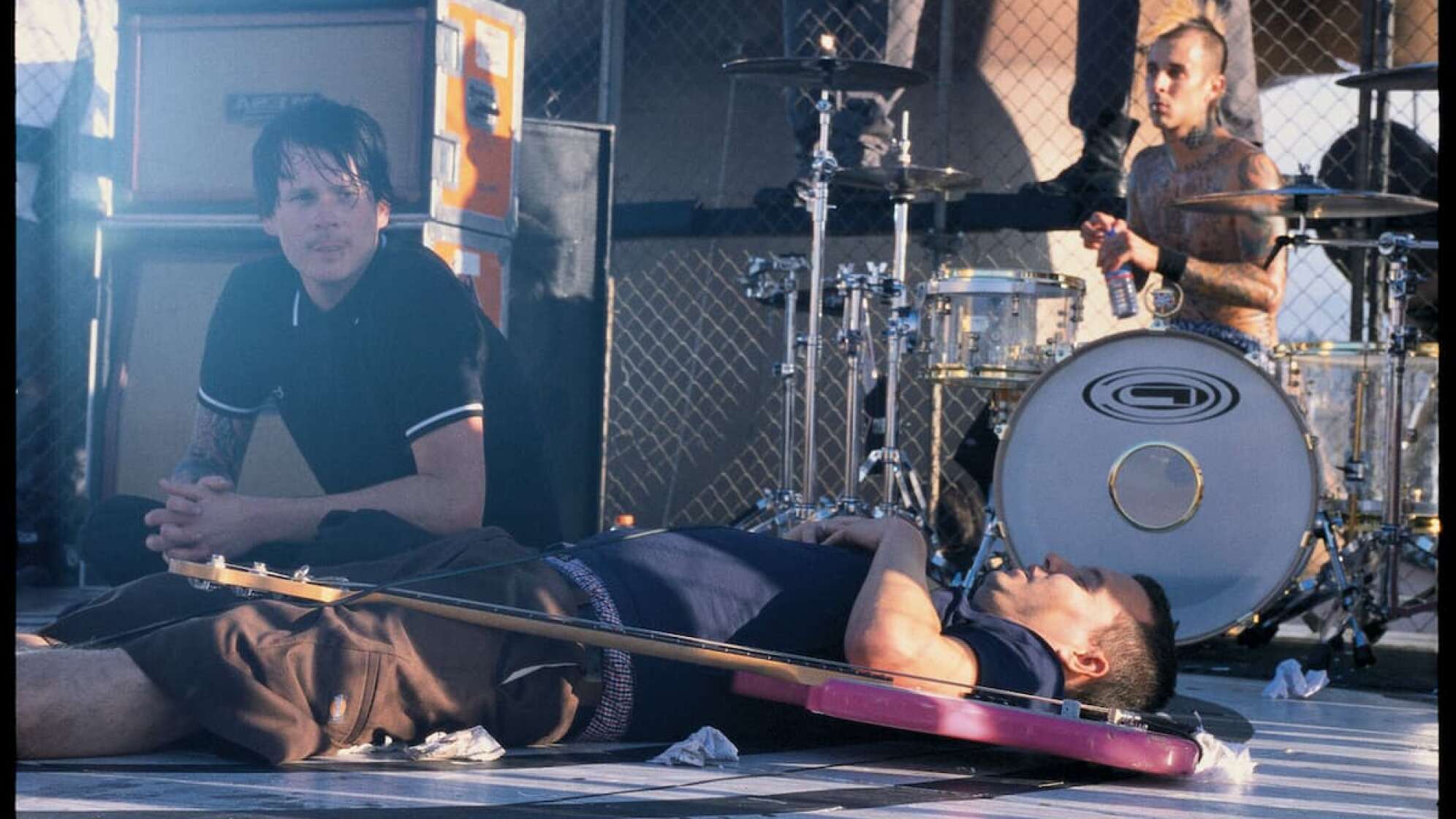 Blink-182 sitzend und liegend auf einer Bühne