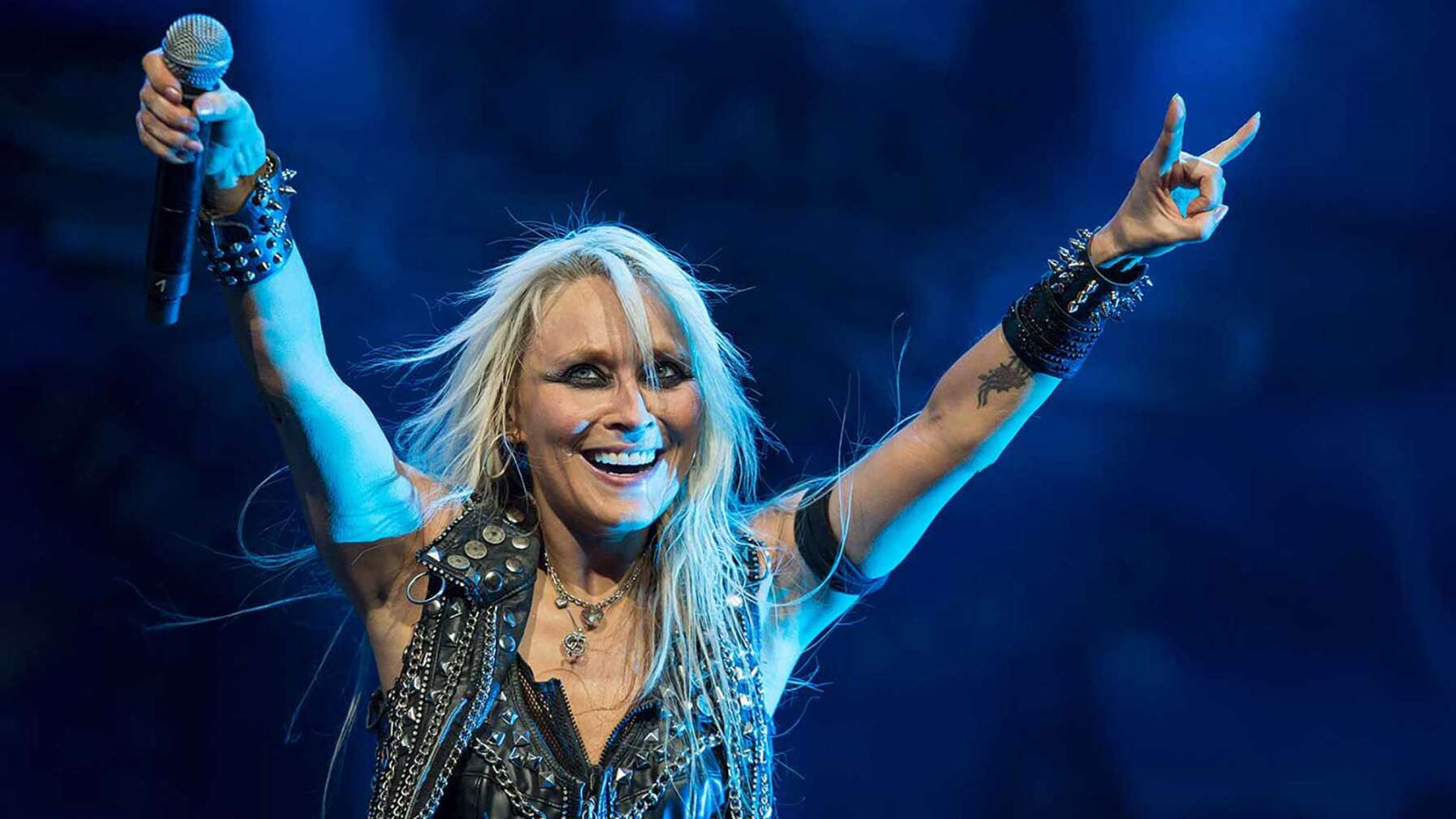 Metal-Sängerin Doro Pesch streckt ihre Hände auf der Bühne in die Luft.
