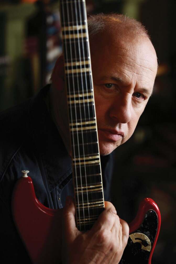Mark Knopfler hält eine Gitarre