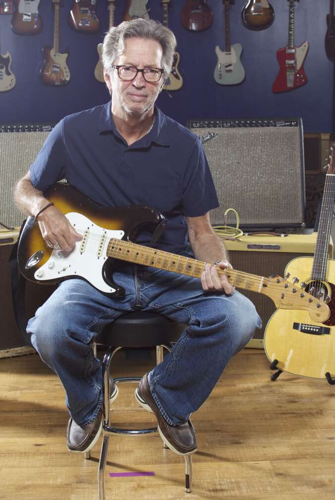 Eric Clapton mit Gitarre auf einem Stuhl sitzend