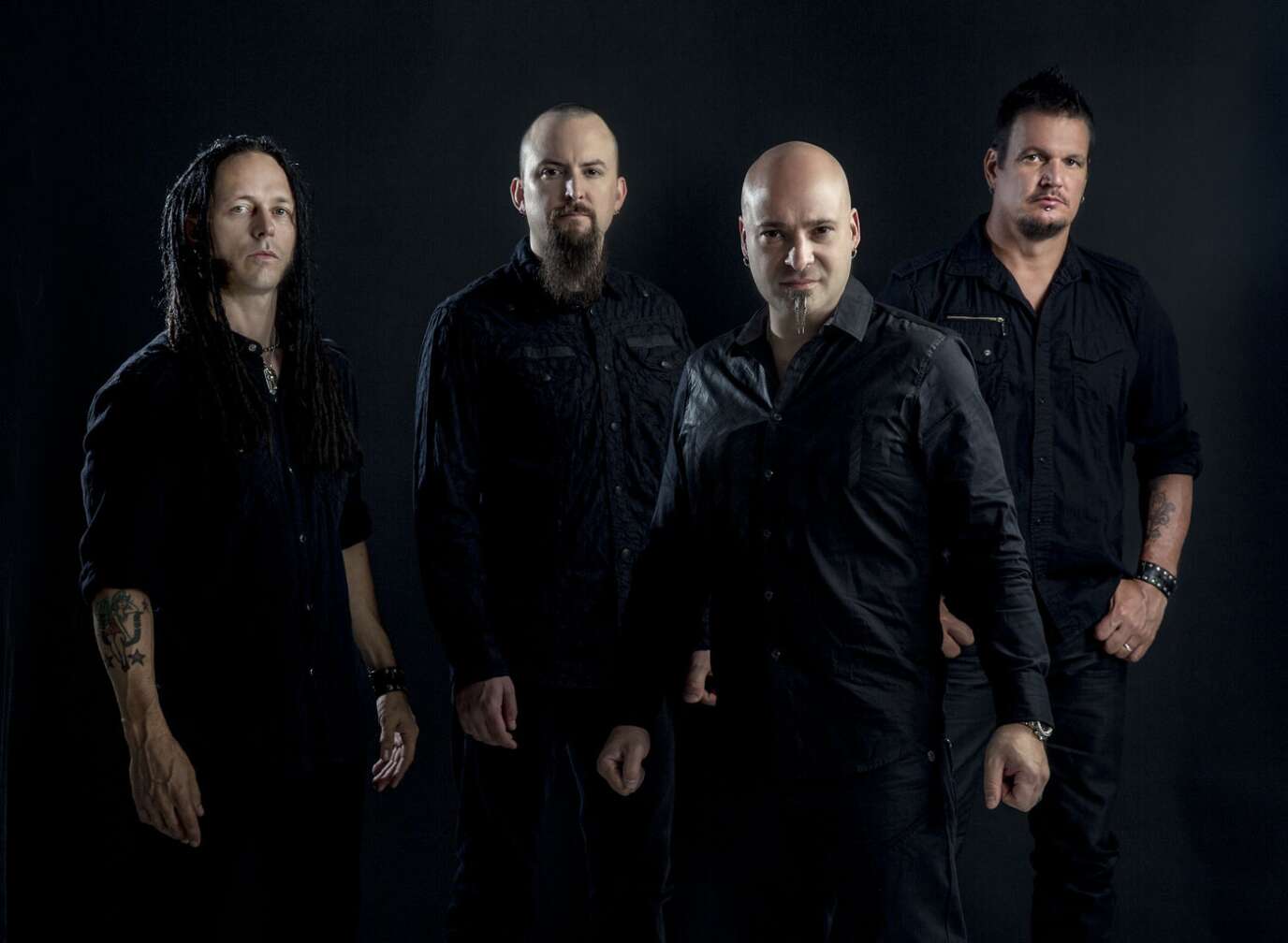Disturbed Group in schwarzen Anzug vor einem schwarzen Hintergrund in die Kamera schauend