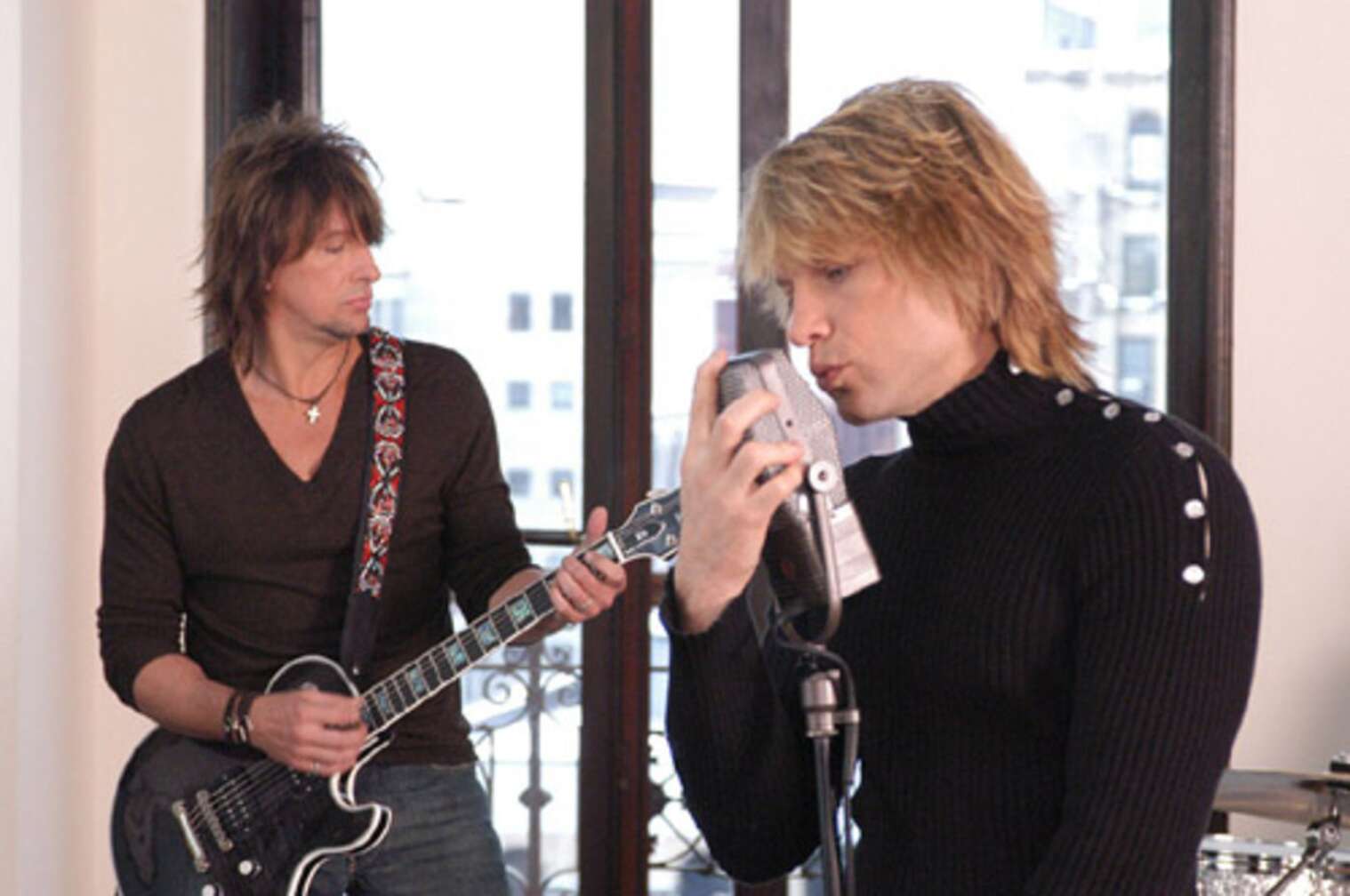 Bon Jovi bei einem Videodreh mit Gitarre und Mikrofon