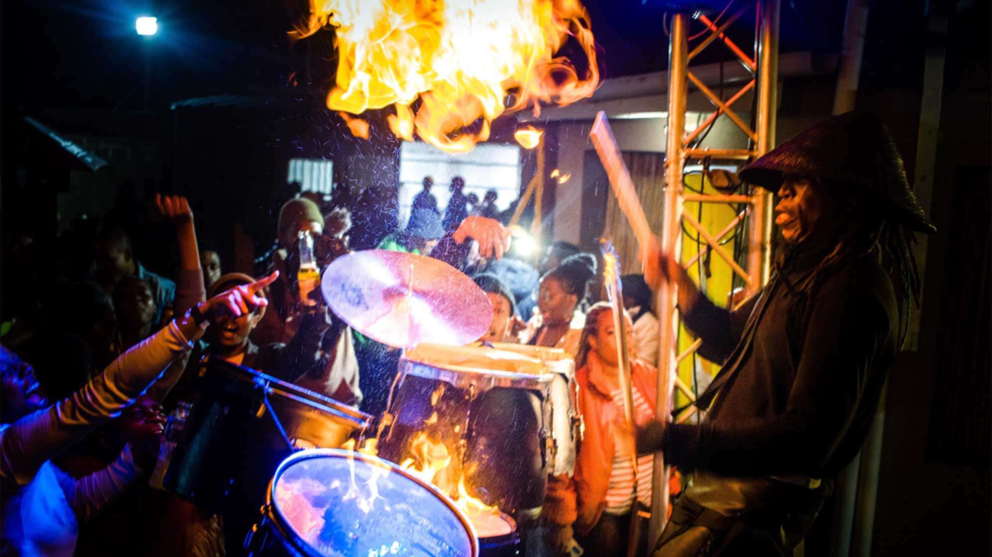 Mann spielt auf einem brennenden Drum Set