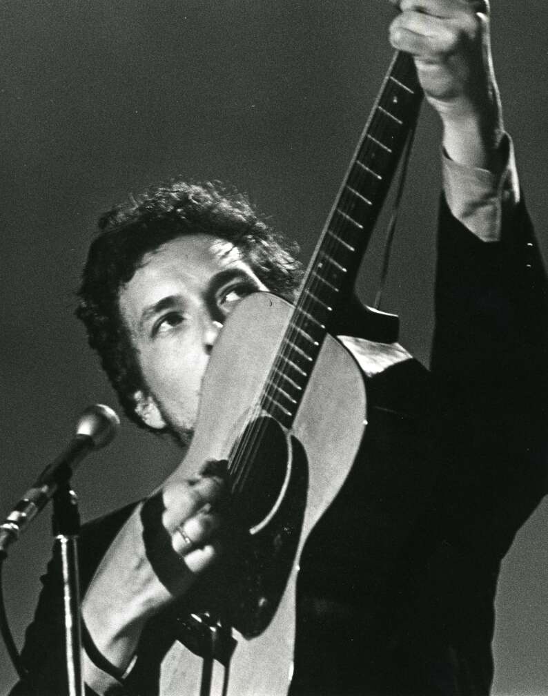 Bob Dylan spielt seine Gitarre auf Kopfhöhe, auf der Bühne