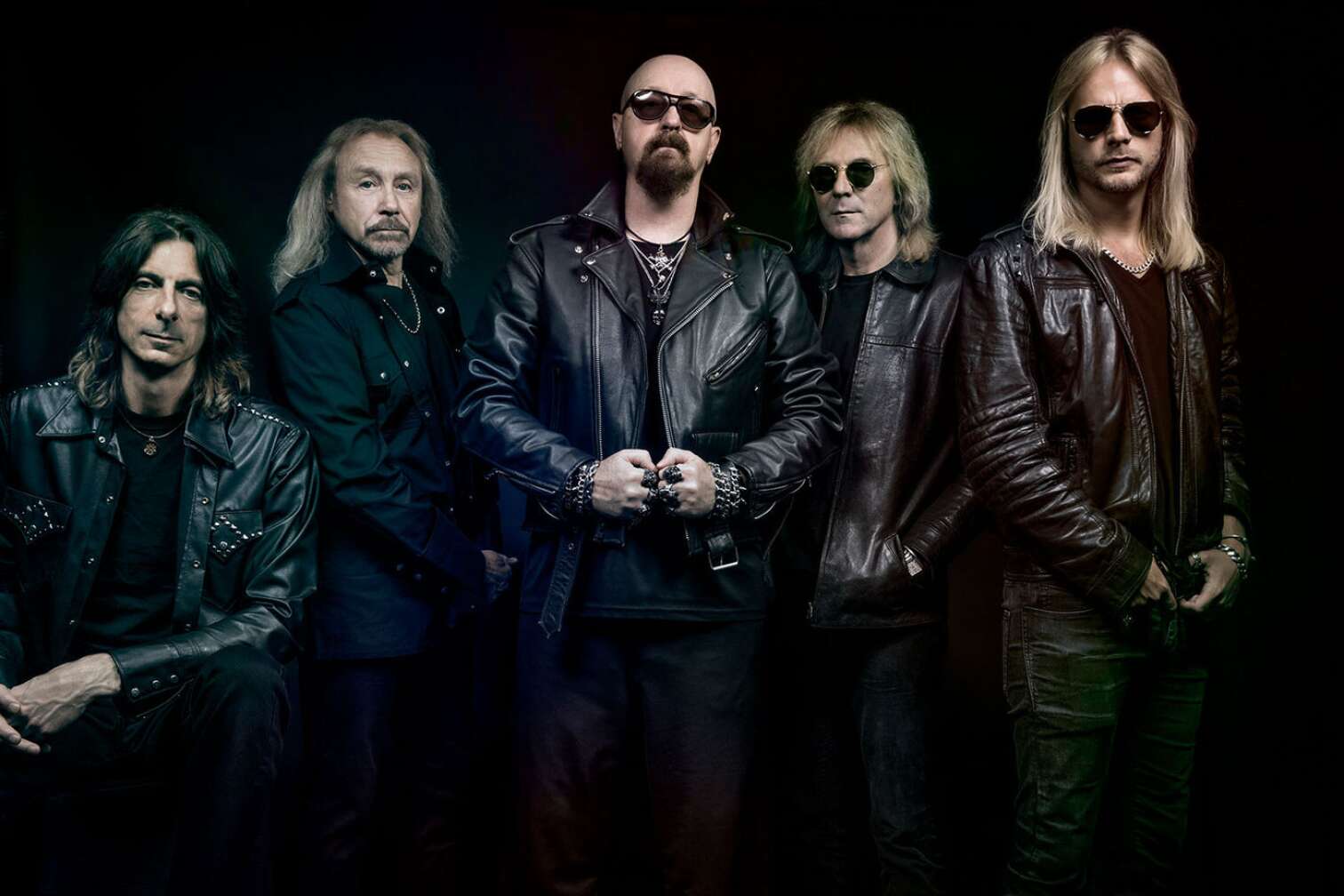 Judas Priest als Gruppenbild vor einem schwarzen Hintergrund