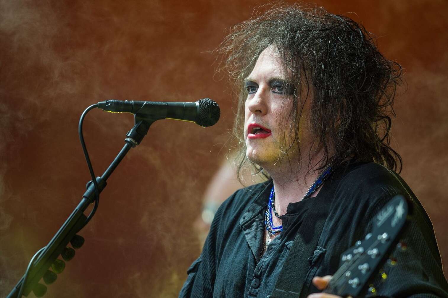 Robert Smith beim Singen auf der Bühne mit Gitarre