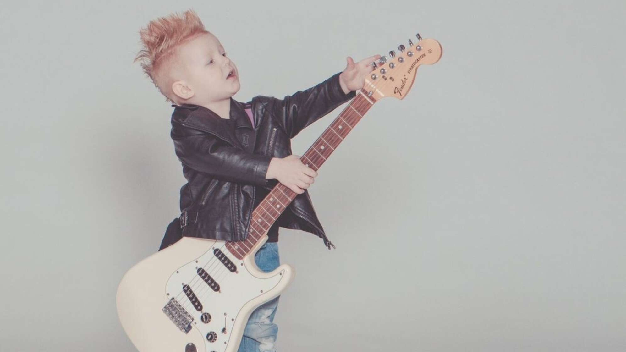 Kind in Lederjacke mit E-Gitarre